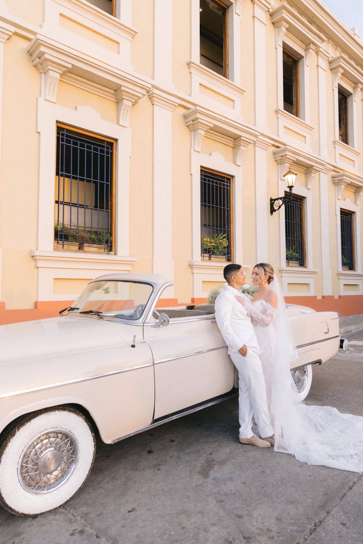 Editorial wedding portrait — couple kissing beneath a colonial bell tower