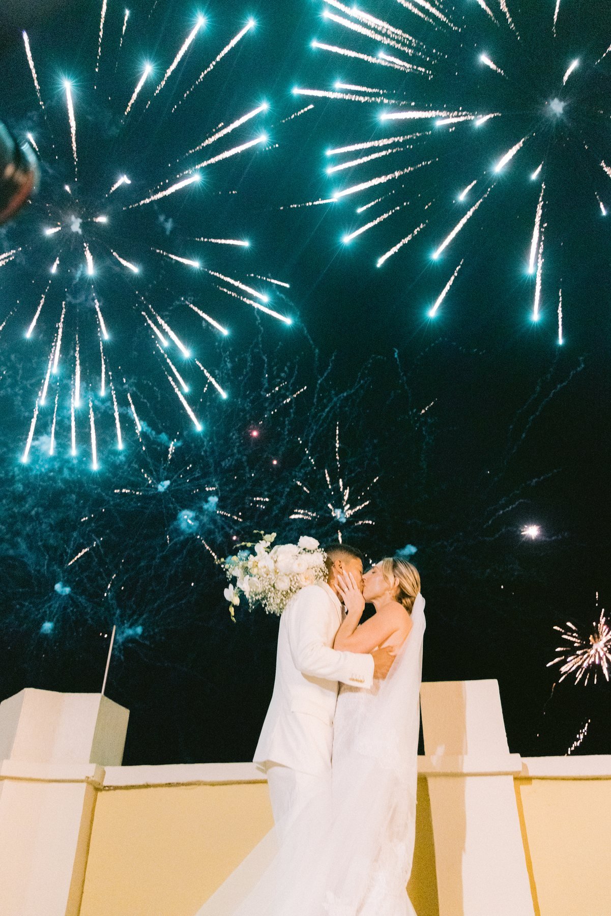 Editorial wedding photography — forehead kiss beneath fireworks