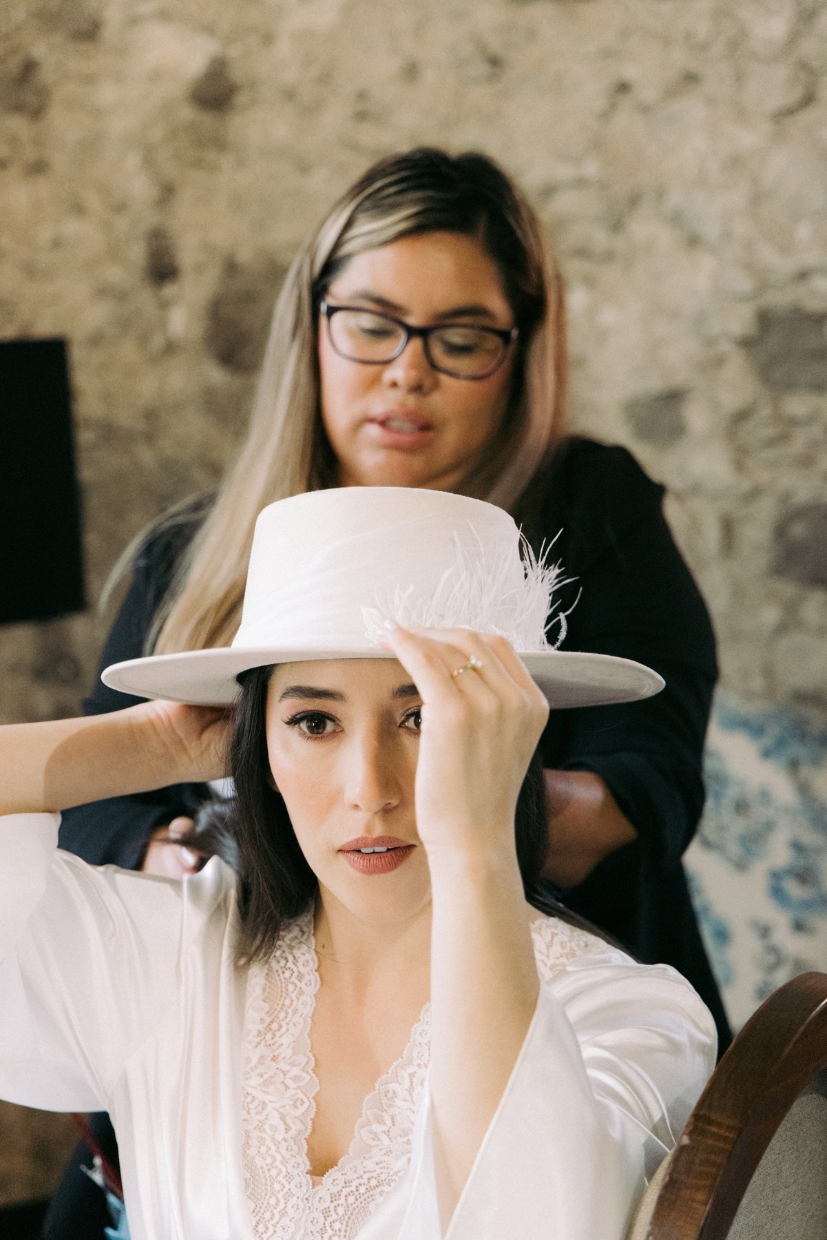 Fashion-forward editorial bridal portrait in a wide-brim hat and sunglasses