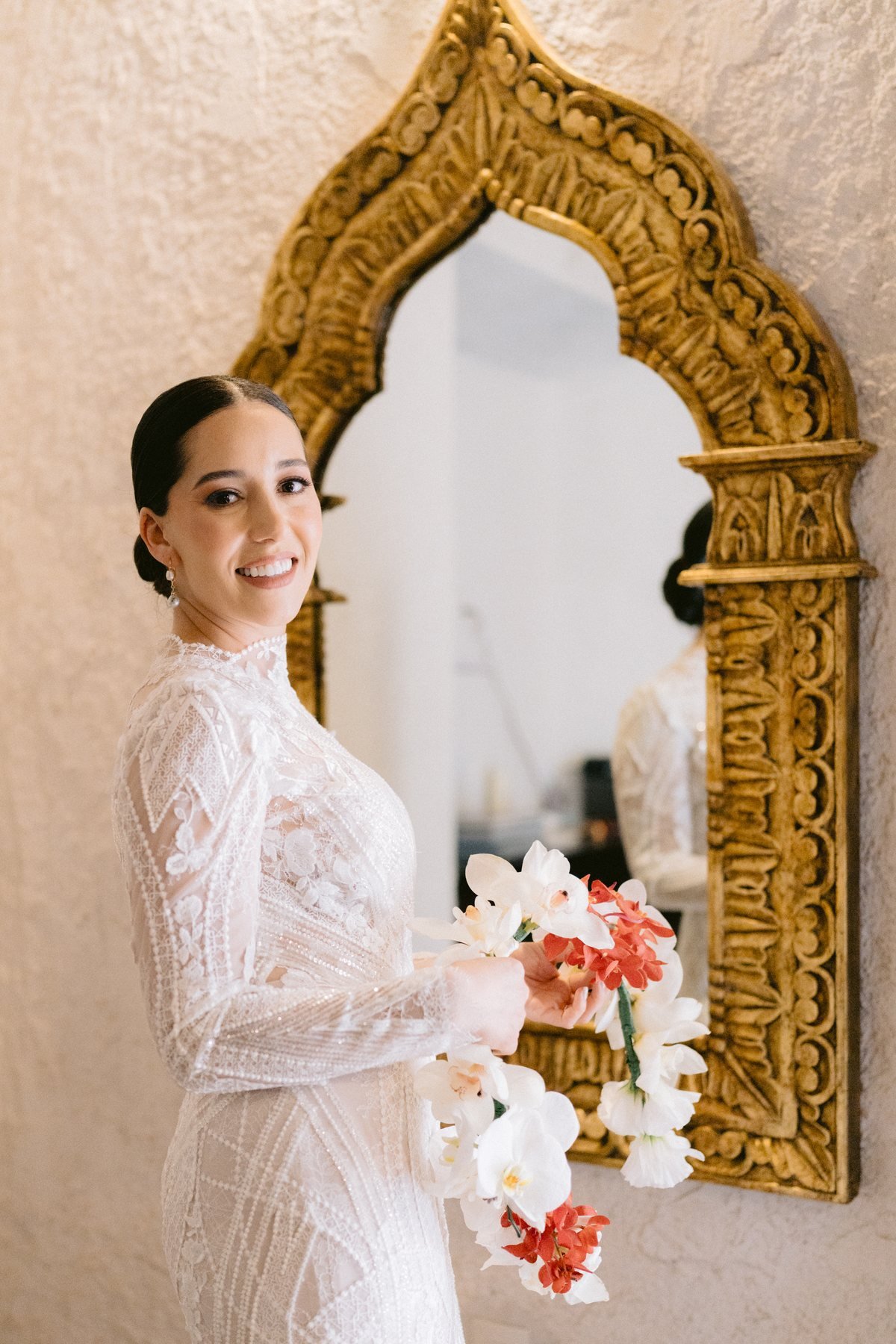 Editorial wedding photography — bride with orchid bouquet beside a gilded Moorish mirror