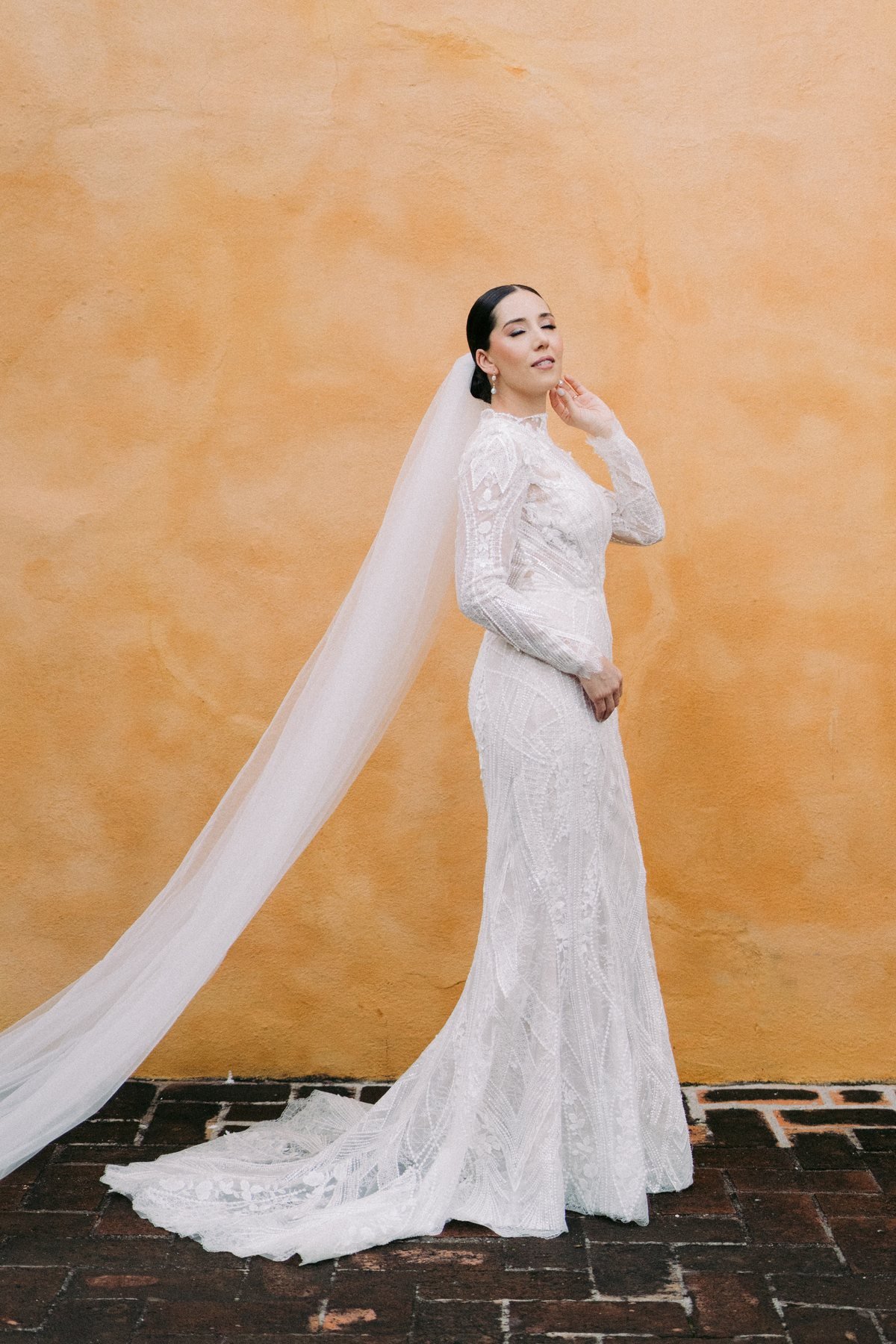 Editorial bridal portrait against a terracotta wall with a circular window