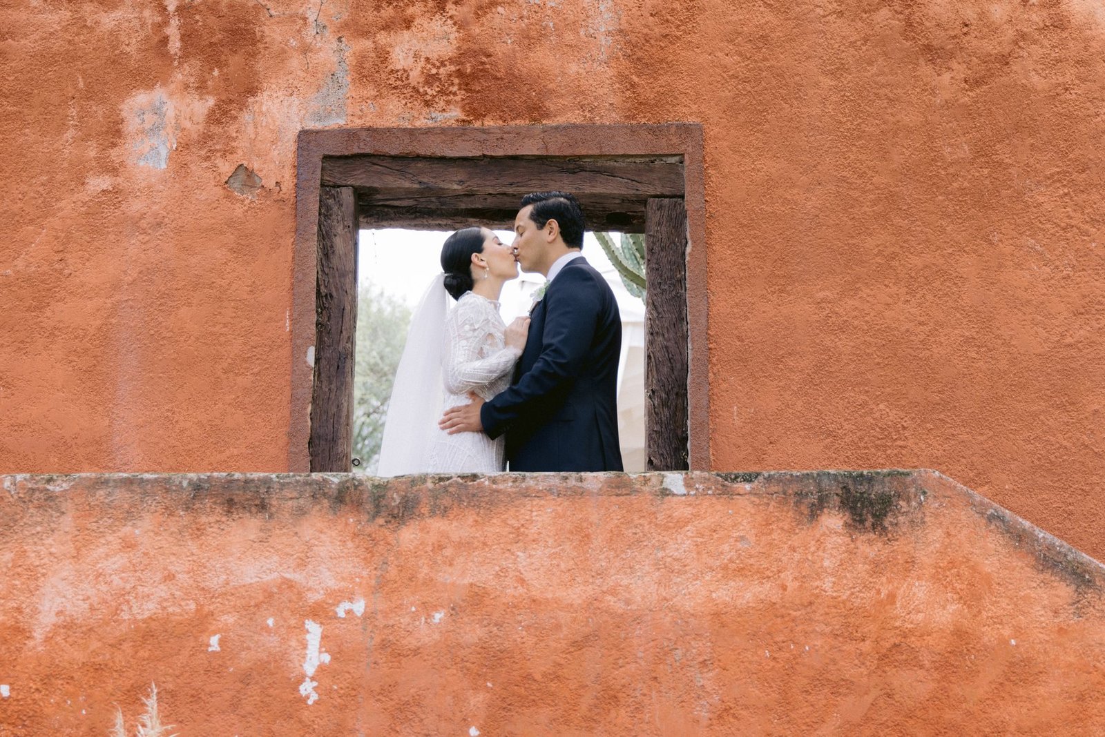Editorial couple portrait framed inside a wall window opening