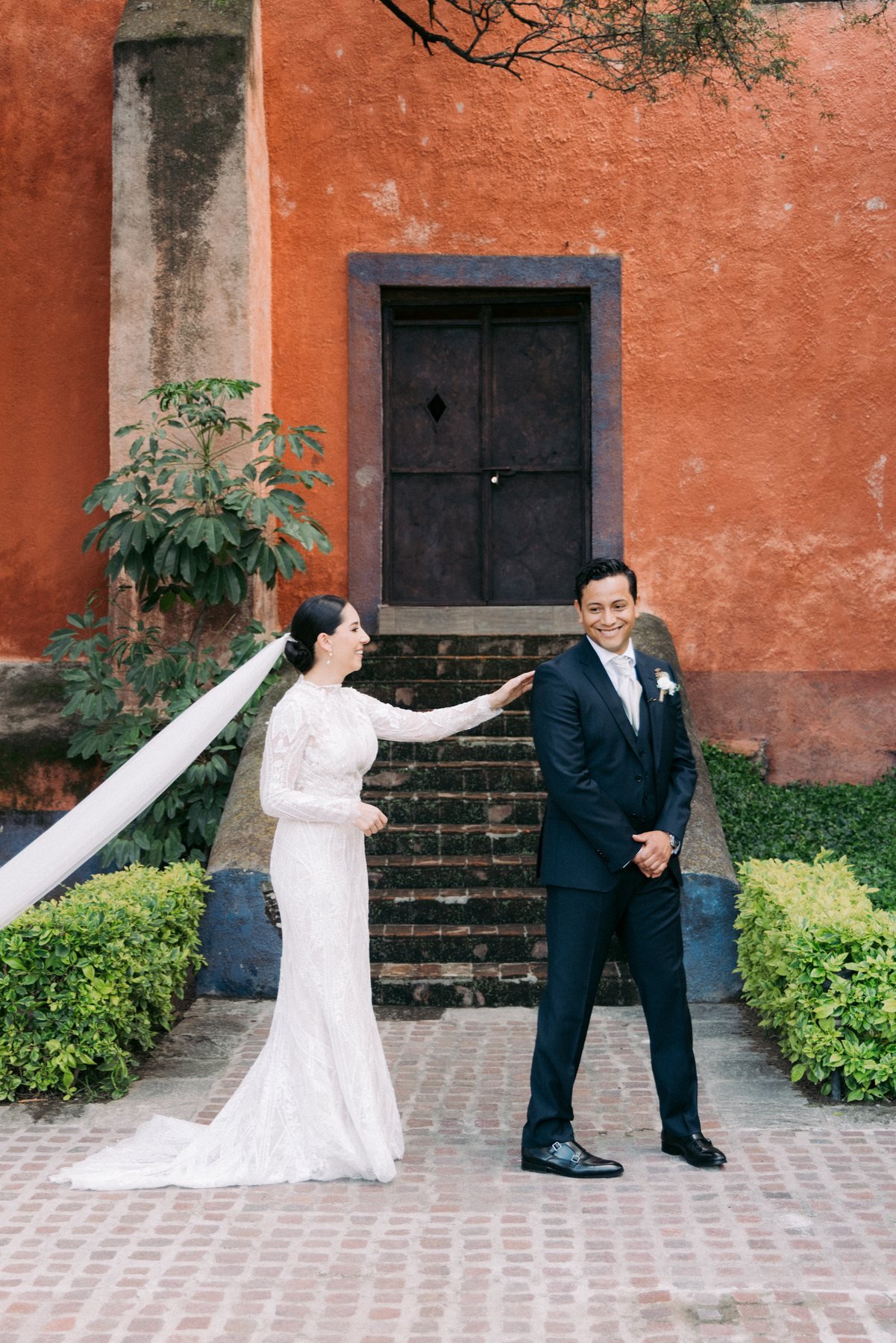 Windswept bridal veil against a terracotta colonial wall, editorial wedding photography
